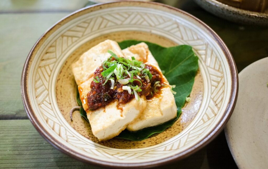 Sliced tempeh and tofu on a wooden board with vegetables