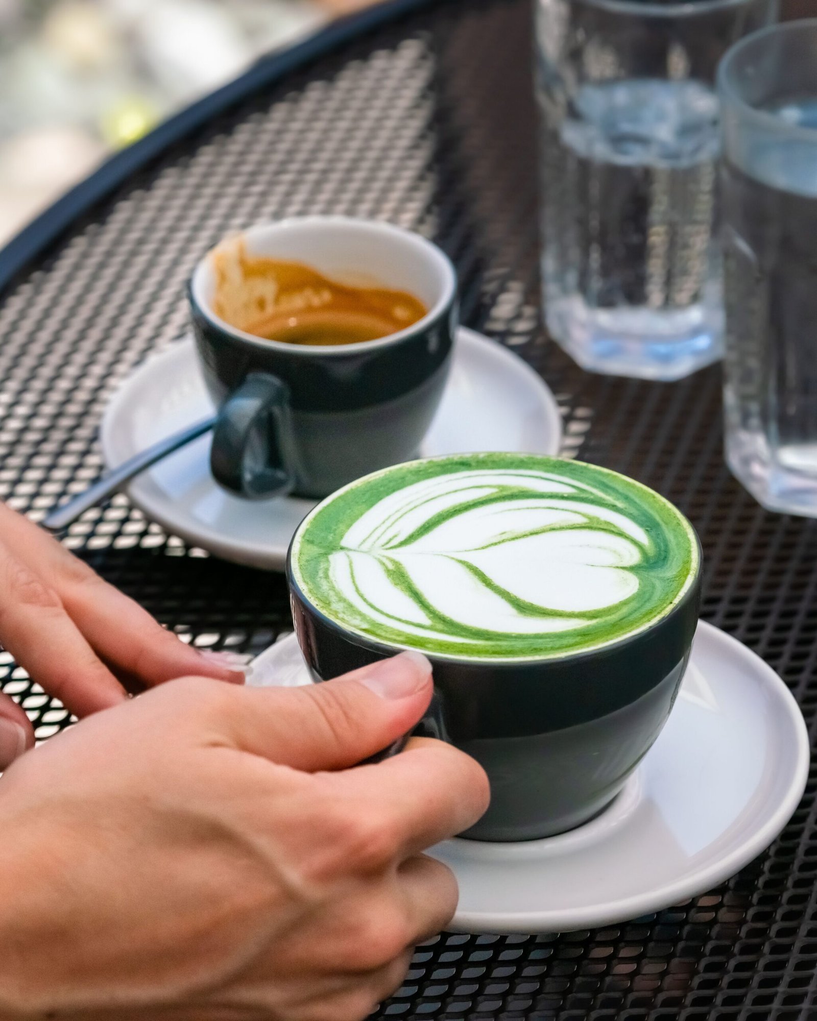 Green matcha drink beside a black coffee cup